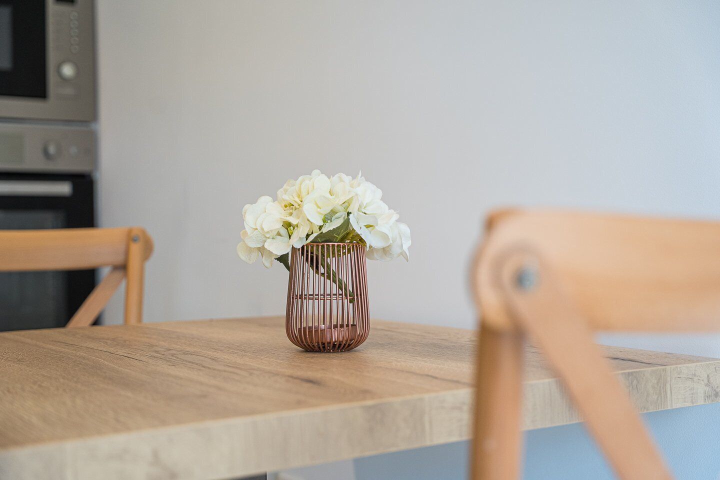 Ein Holztisch mit einer Vase weißer Blumen.