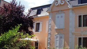 Um edifício com fachada cor de pêssego, persianas brancas e molduras decorativas nas janelas.