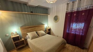 Een slaapkamer met een houten bed, nachtkastjes, een plank en een raam met gordijnen.