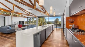 A modern kitchen with a large island, wooden beams, and a view of the outdoors. - Absolute Beachfront | 5BR Family Escape (Pindimar)
