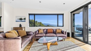 Ein modernes Wohnzimmer mit Ledersofa, Glastisch und großem Fenster mit schöner Aussicht.