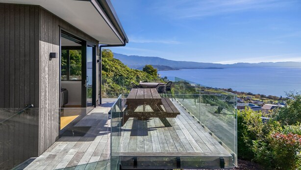 Ein modernes Haus mit einem Glasbalkon und einem herrlichen Blick auf das Meer und die Berge.