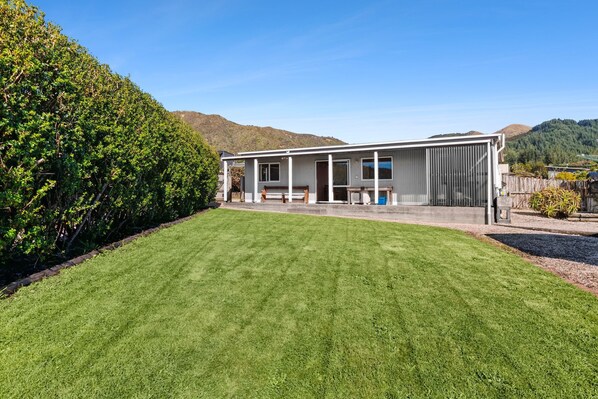 A modern house with a large lawn and a view of hills in the background.