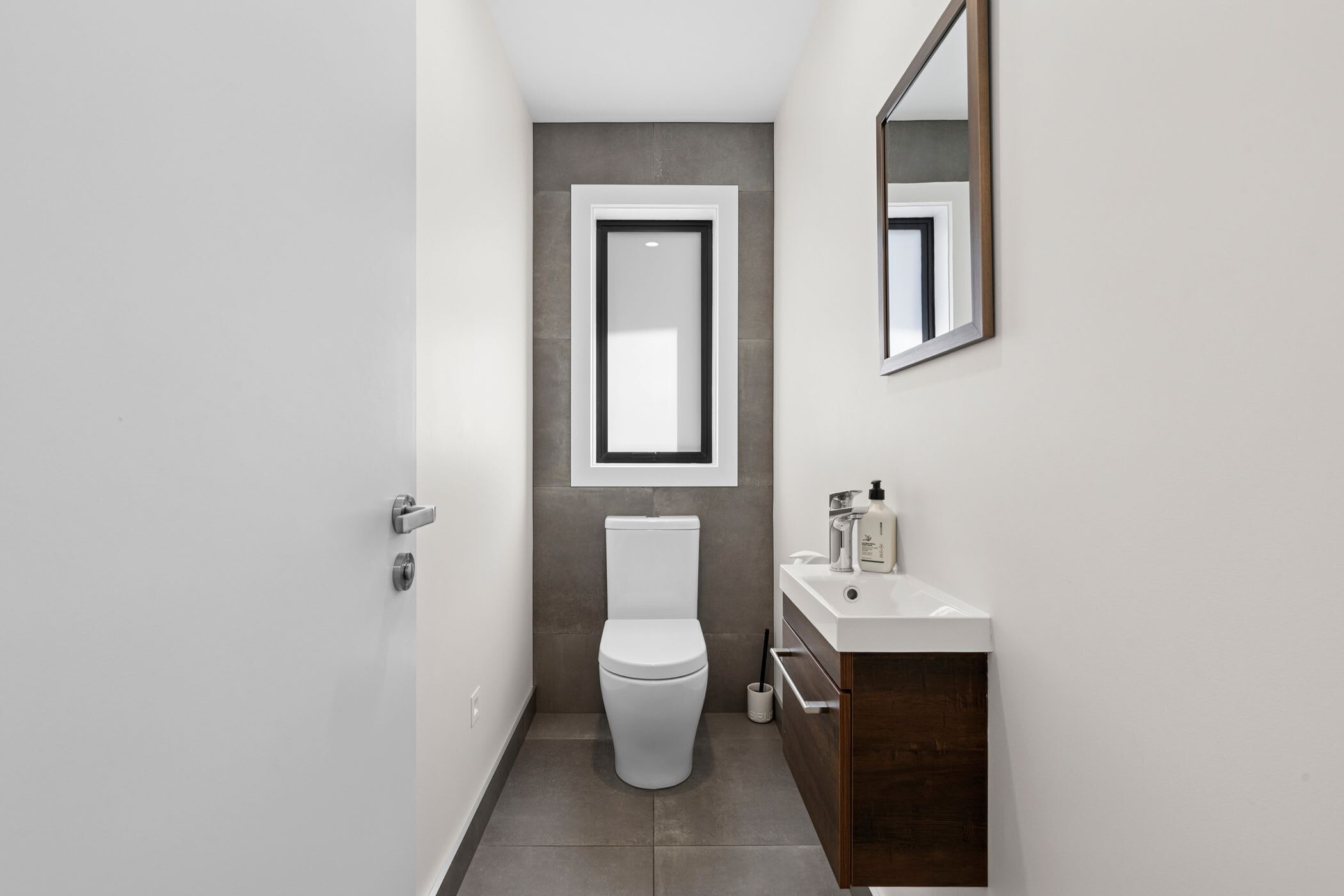 Une salle de bain moderne avec des toilettes, un lavabo et un miroir.