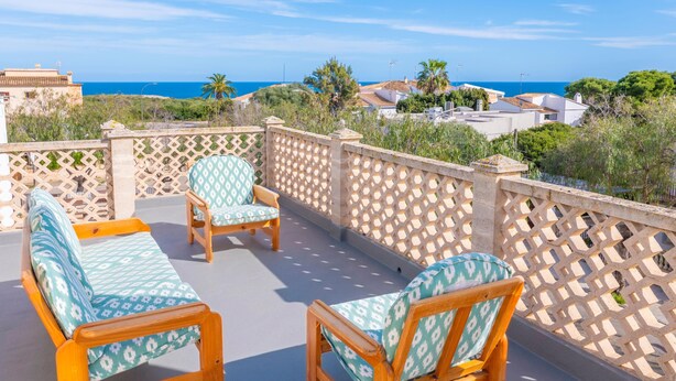Um terraço com vista para o mar, mobiliado com um sofá e duas cadeiras.