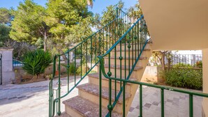 Uma escadaria com corrimãos verdes que leva a uma parede bege.