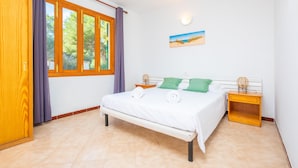 Quarto com cama, mesa de cabeceira de madeira e janela com cortinas.