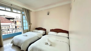 A hotel room with two beds, a balcony, and a view of buildings outside. - Yên hostel (Cam Ly - Da Lat)