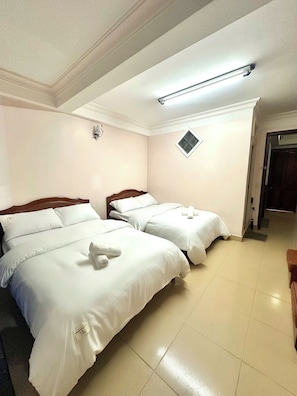 A hotel room with two beds, a ceiling light, a small window, and a door. - Yên hostel (Da Lat)