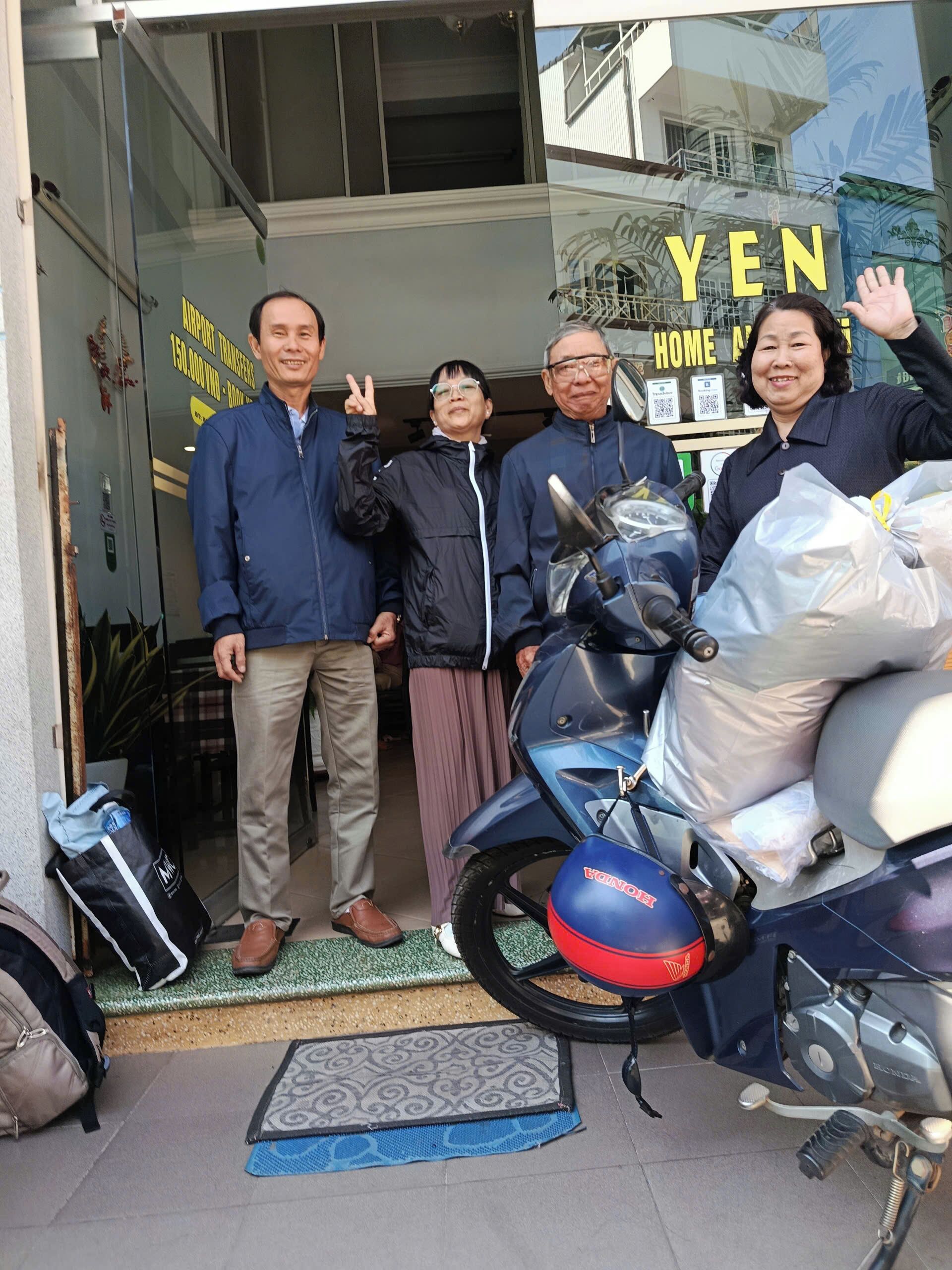 Un grup de persones al davant d'un edifici, amb una moto aparcada a prop.