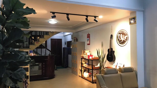 A living room with a sofa, a piano, and a staircase leading to another room. - Yên hostel (Cam Ly - Da Lat)
