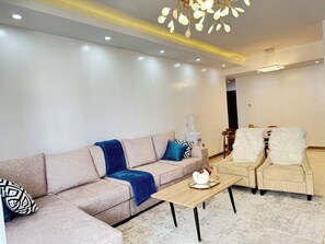 A modern living room with a sectional sofa, a wooden coffee table, and two armchairs. - FamilyNest Kilimani with Gym, Heatedpool n/r Yaya, ChinaCity, Malls, Restaurants (Nairobi)
