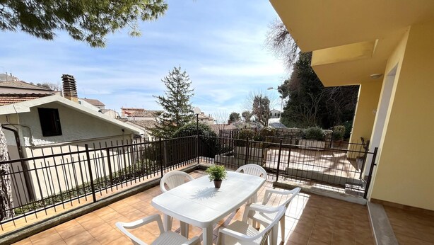 A balcony with a white table and chairs, a potted plant, and a view of the neighborhood. - Bilo onda, near the sea and downtown with a/c (Numana)