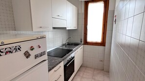 A compact kitchen with white cabinets, a black countertop, and a window with a wooden frame. - Bilo onda, near the sea and downtown with a/c (Numana)