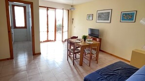A living room with a blue sofa, a dining table with chairs, a TV, and a ceiling fan. - Bilo onda, near the sea and downtown with a/c (Numana)