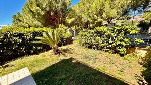 A garden with a variety of plants and trees, a paved walkway, and a metal fence. - Two-room apartment Leonardo - Sirolo (Sirolo)