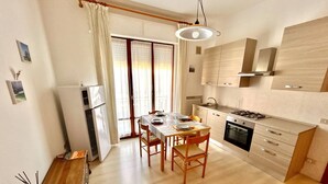 Una cocina moderna con comedor, armarios de madera y un ventanal con cortinas.