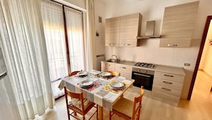Una cocina moderna con armarios de madera, una estufa a gas y un comedor para cuatro personas con mesa y sillas.