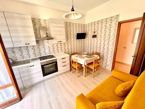 A compact kitchen with a dining area, a sofa, and a TV. - TRILO LARA with wifi and parking (Sirolo)
