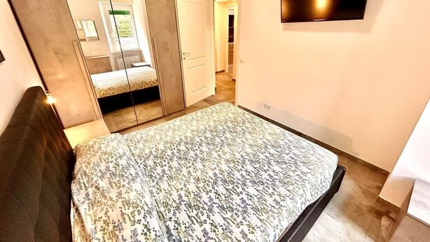 A bedroom with a bed, a wardrobe, a mirror, and a TV on the wall. - Two-room apartment Leonello with garden and a/c (Numana)