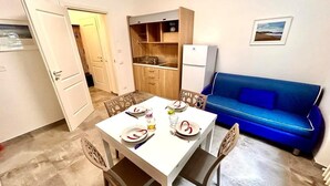 A compact living space with a dining area, kitchenette, and a blue sofa. - Two-room apartment Leonello with garden and a/c (Numana)