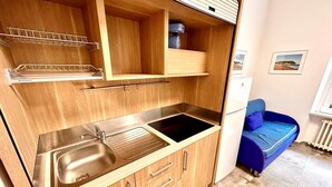 A compact kitchen with a sink, a countertop, and wooden cabinets. - Two-room apartment Leonello with garden and a/c (Numana)