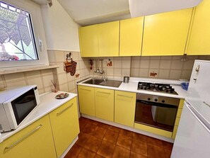 A kitchen with yellow cabinets, a white microwave, a sink, a stove, and a refrigerator. - Three-room apartment Antonella with sea view, a/c and p. auto (Numana)