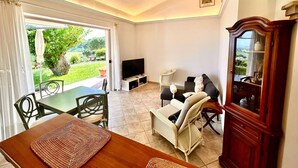 A room with a dining table, chairs, a sofa, a TV, and a cabinet. - Villa Margherita, with garden, sea view and wifi (Numana)