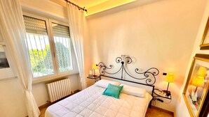 A neatly made bed with a quilted white duvet, a green pillow, and a black metal headboard. There are two bedside lamps on either side of the bed. - Villa Margherita, with garden, sea view and wifi (Numana)