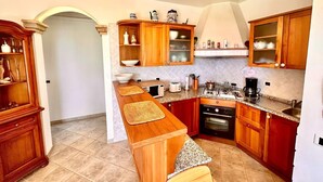 A kitchen with wooden cabinets, a built-in oven, a microwave, and a gas stove. - Villa Margherita, with garden, sea view and wifi (Numana)