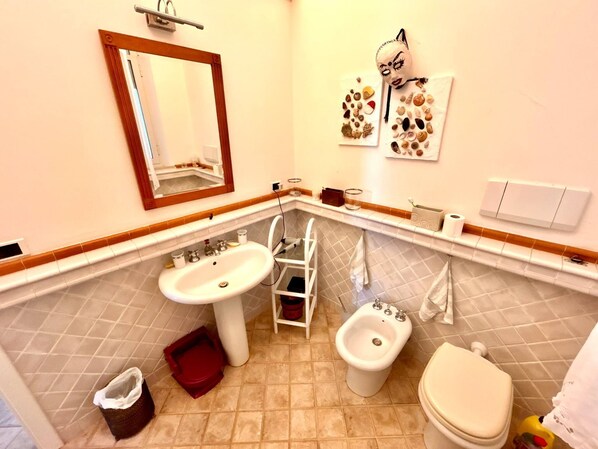 A bathroom with a sink, bidet, toilet, and a mirror.