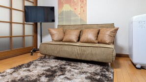 Ein Zimmer mit einer Couch, einem Fernseher, einer Wanddekoration und einem Kühlschrank.