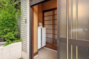 A narrow entrance with a wooden door and a small cabinet with a sign. - Iriya 101 Family Apartment Max 6  (Tokyo)