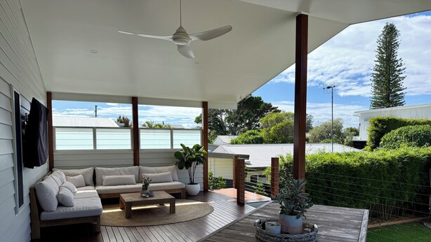 Un espacio al aire libre techado con sofá, una mesa de centro y plantas en macetas.