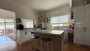 Una cocina moderna con una isla central, taburetes de bar y vistas al exterior.