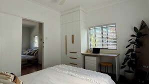 Un dormitorio con cama, escritorio, armario y ventilador de techo.