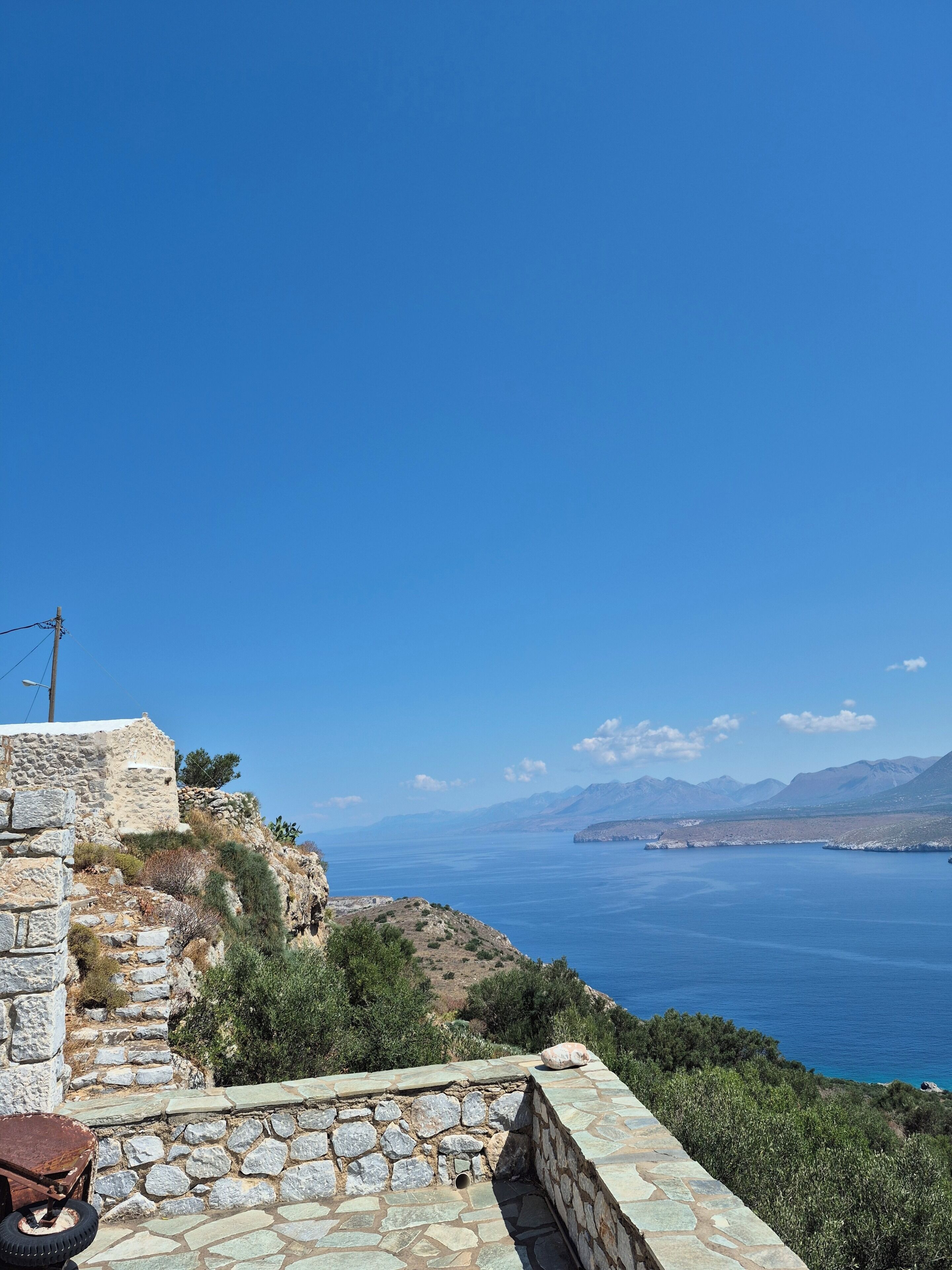 A stone building with a view of the sea and mountains.