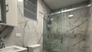 Casa de banho com sanita, lavatório e chuveiro.