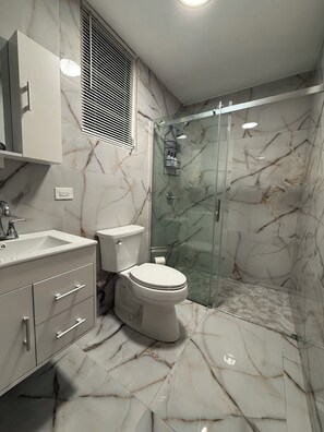 Un baño con inodoro, lavamanos y ducha.