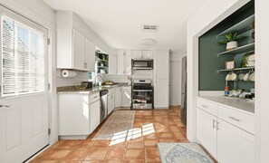 Une cuisine moderne avec des meubles blancs, un four encastré, un four à micro-ondes et un réfrigérateur.