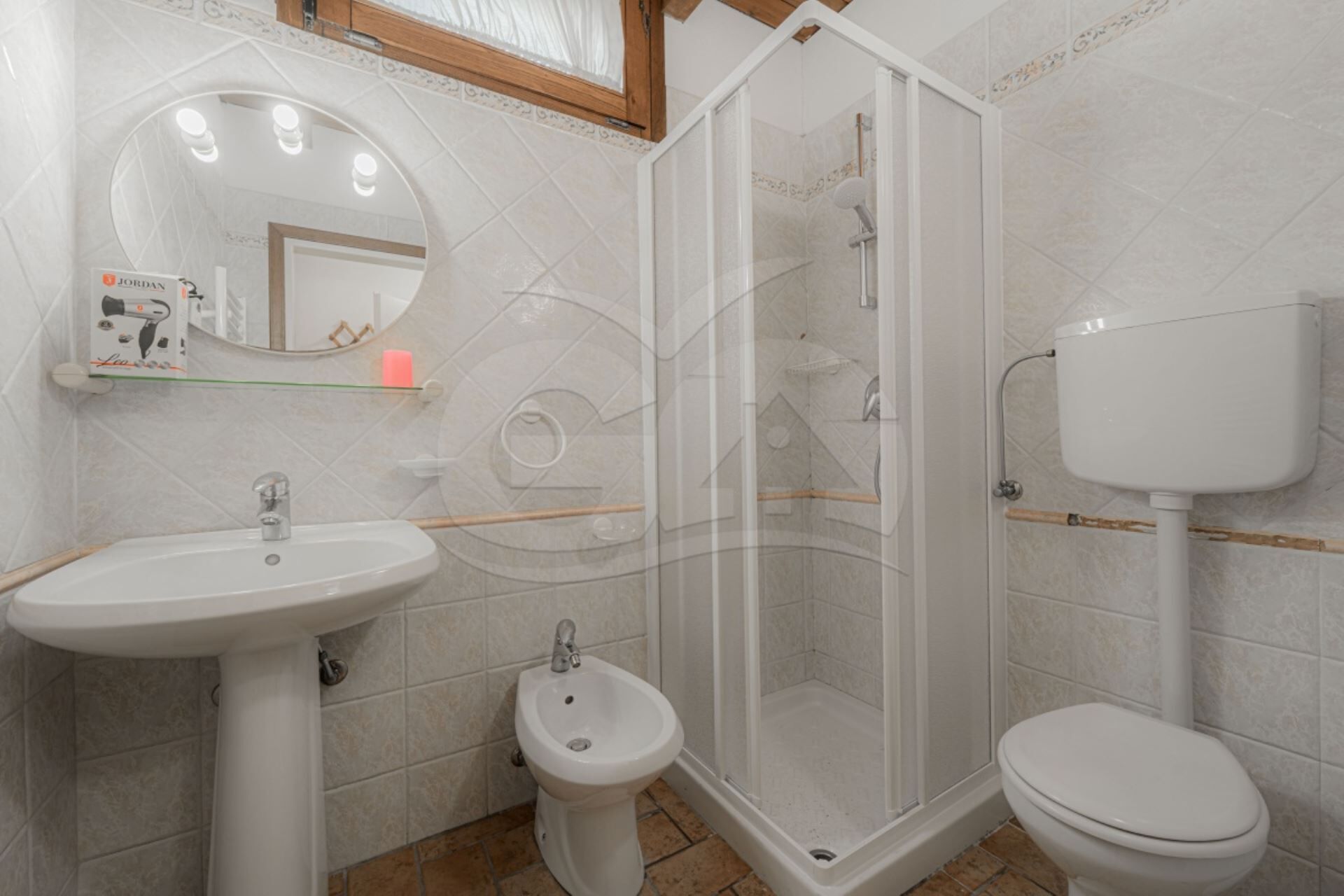 A bathroom with a sink, bidet, toilet, and glass-enclosed shower.
