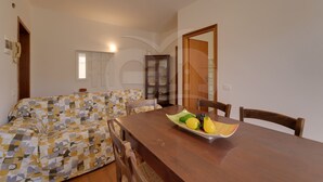 Un coin repas avec une table en bois, des chaises et un panier de fruits.