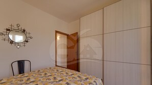 Une chambre à coucher comprenant un lit, une chaise, une armoire et un miroir fixé au mur.