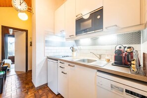 A compact kitchen with white cabinets, a Bosch microwave, a Siemens dishwasher, and a coffee machine. - Apartment Balcon du Léman (Thollon-les-Mémises)