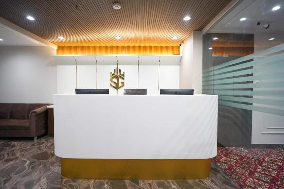 A reception desk with a white and gold base, a wooden ceiling, and a patterned carpet.