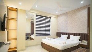 A modern bedroom with a large bed, a built-in TV, and a bedside table. - Hotel SG International  (Kolkata)