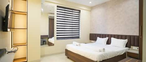 A modern bedroom with a large bed, a built-in TV, and a bedside table.