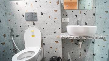 Une salle de bain moderne avec des toilettes blanches, un lavabo et une poubelle.