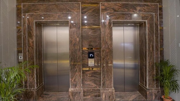 A pair of elevators with marble walls and a digital control panel in the center. - Hotel SG International  (Kolkata)