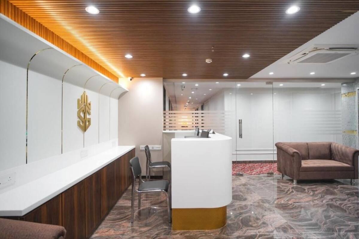A reception area with a wooden ceiling, a reception desk, a brown leather sofa, and a patterned floor.